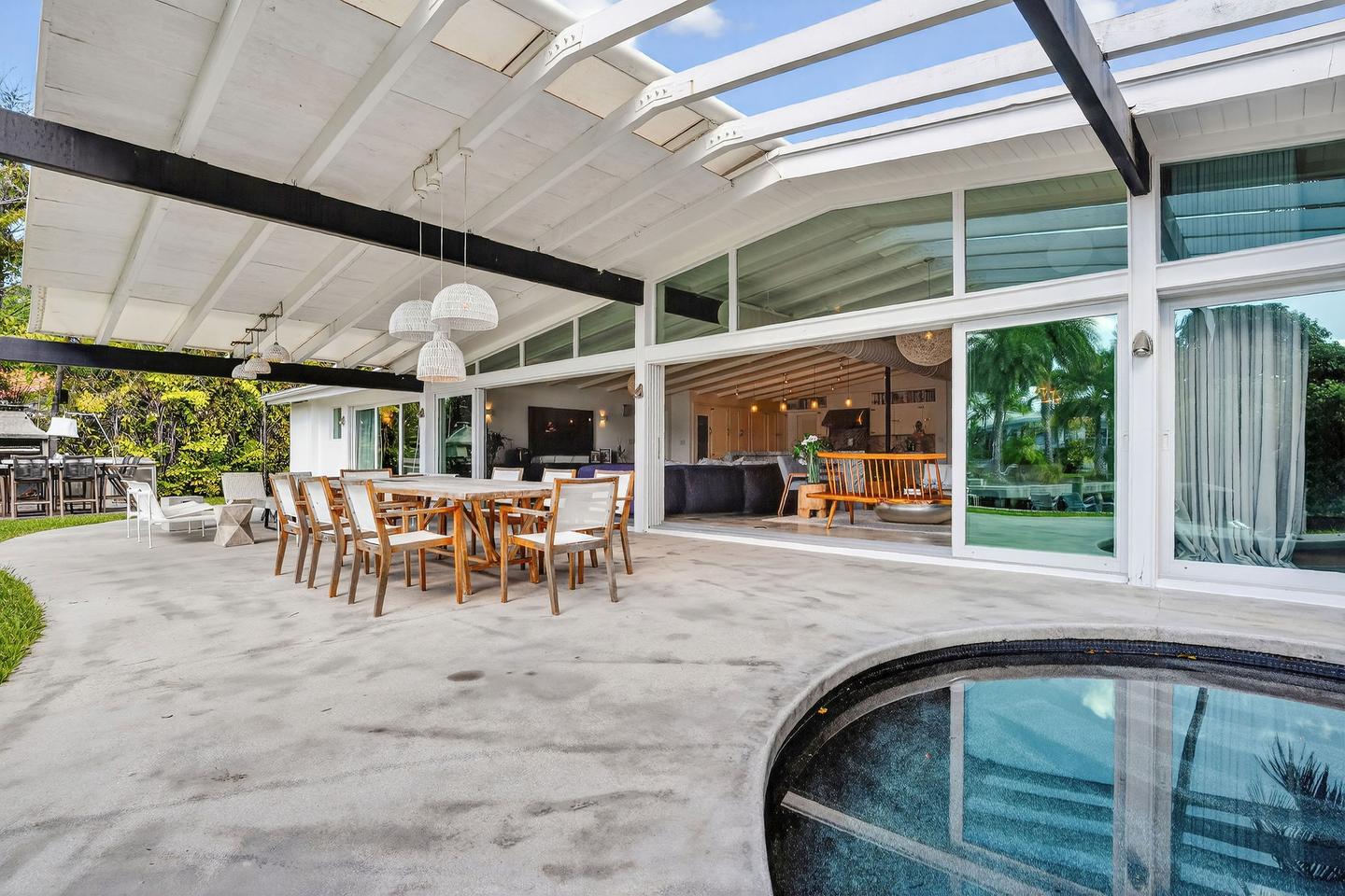 Covered patio and outdoor dining with pool and interior beyond