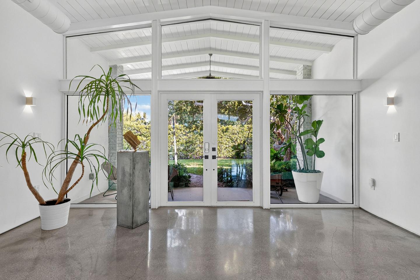 Mid-century modern entry with glass walls and polished concrete