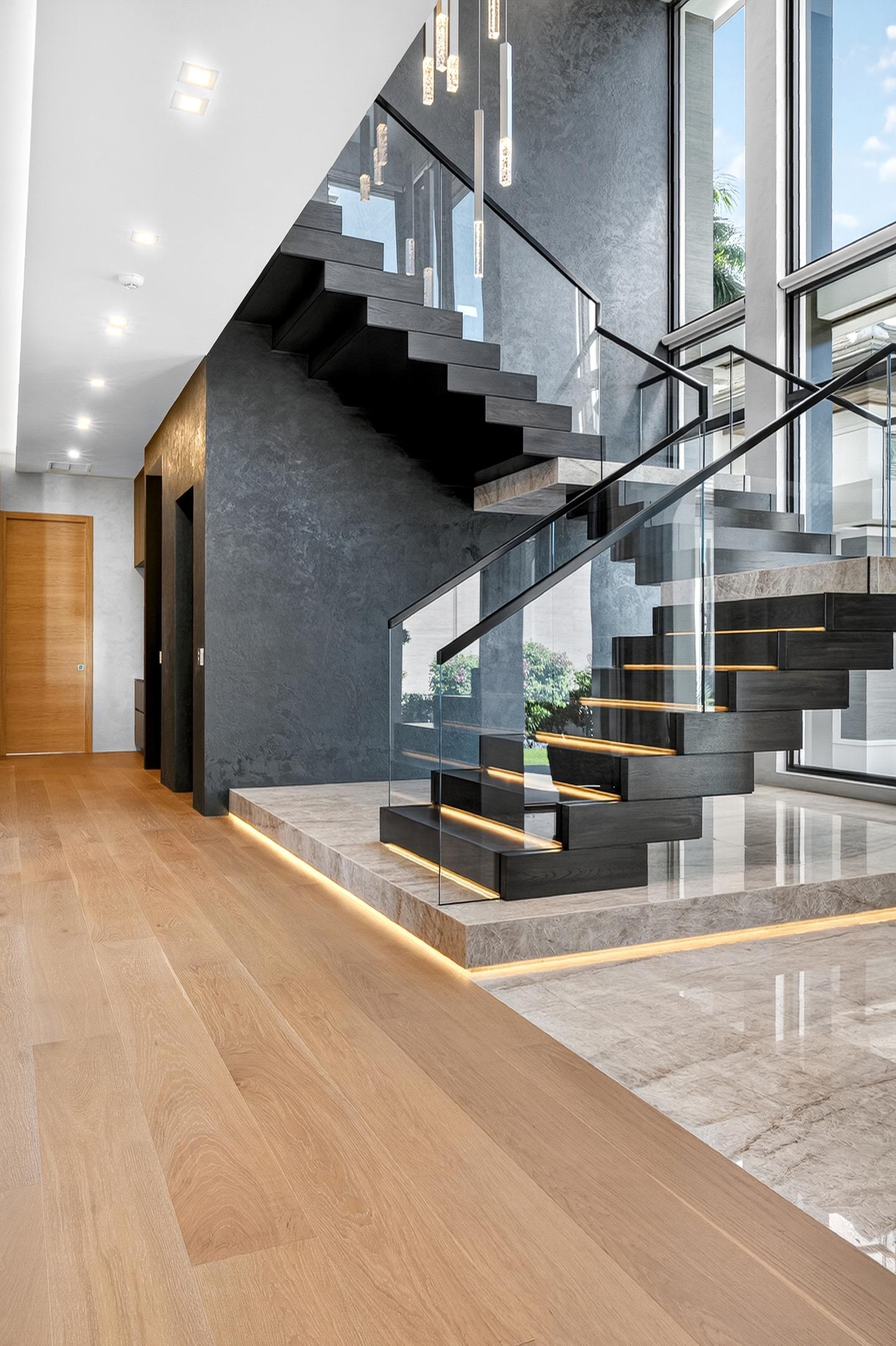 Floating staircase with LED-lit treads and dark textured wall — wide