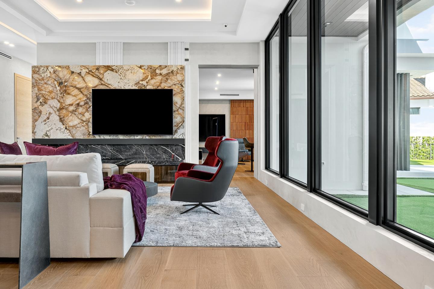 Living room with marble slab feature wall, fireplace, and floor-to-ceiling windows