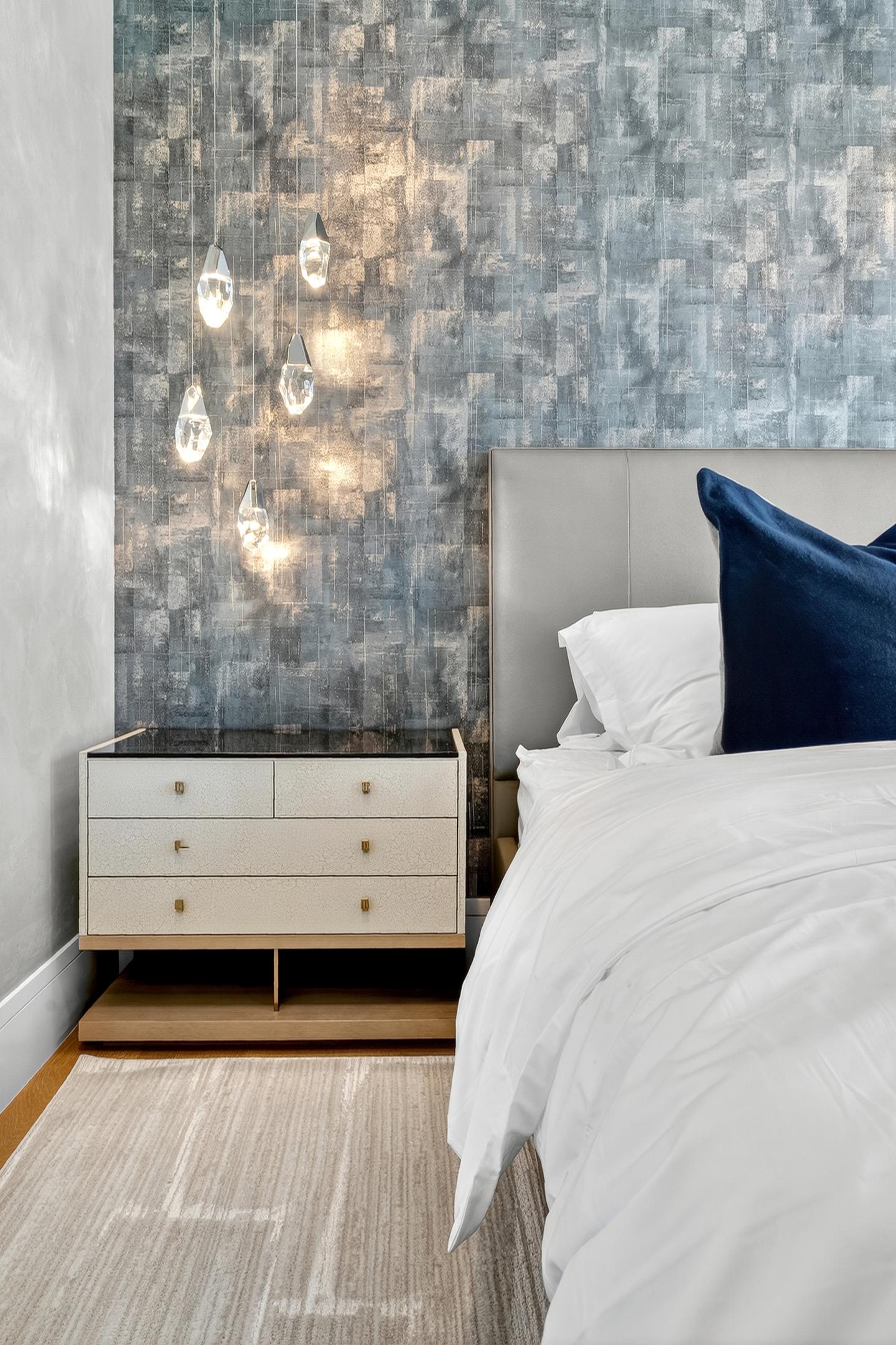 Second bedroom detail — crystal pendants, textured blue wallpaper, and navy pillow