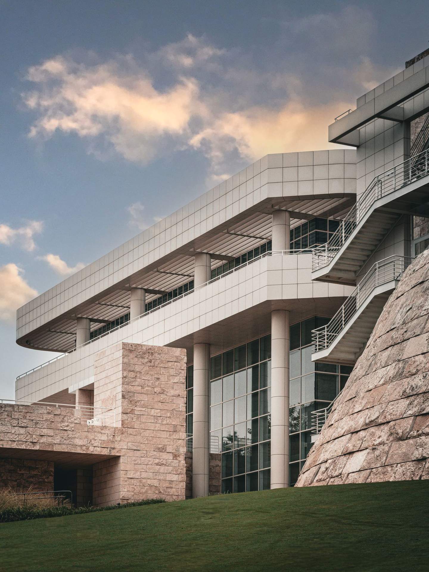 Getty Center north facade with dramatic overcast sky and manicured lawn, travertine cladding catching diffuse morning light