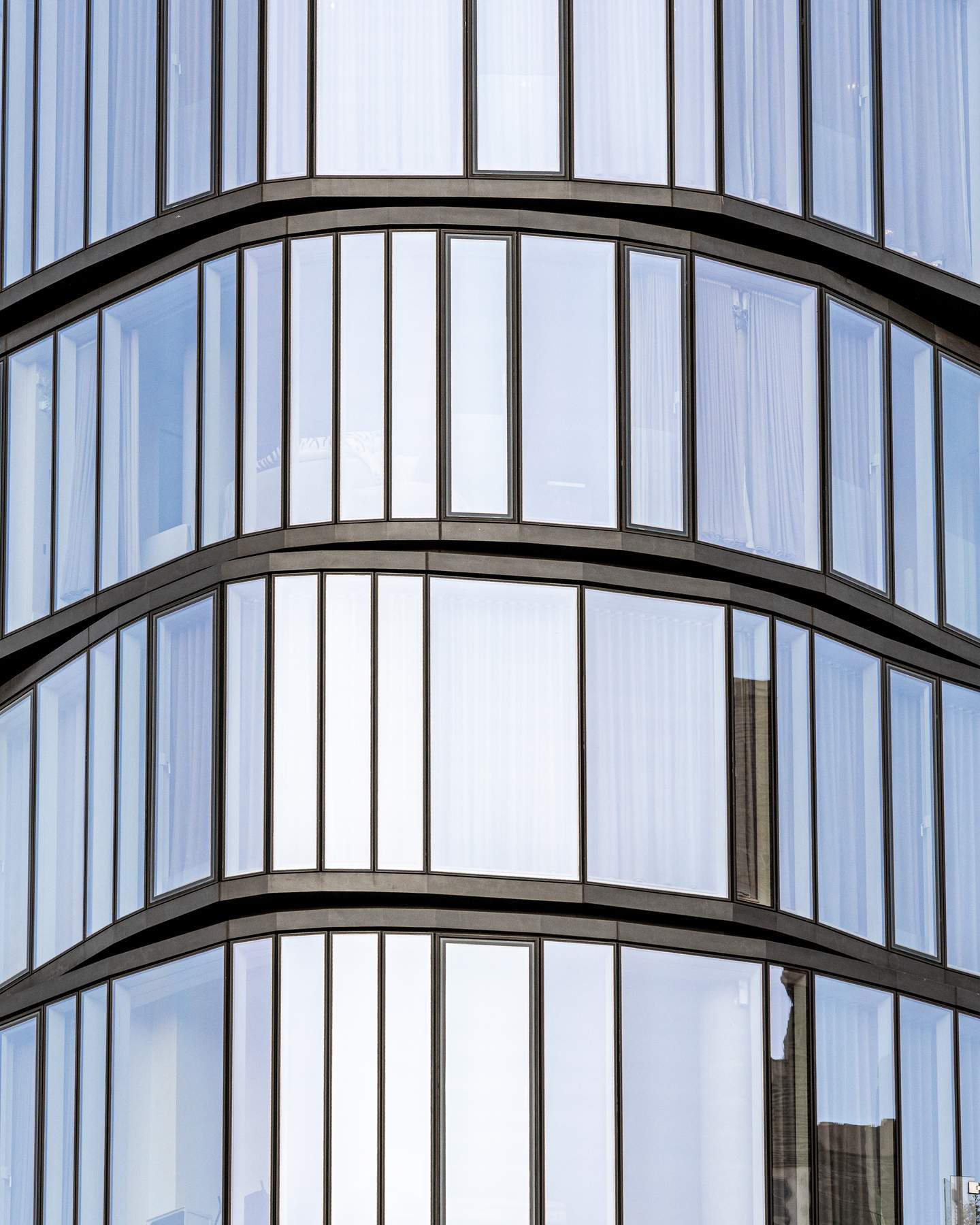 A KPF-designed commercial tower, Midtown Manhattan. Detail of the curved glass curtain wall - each floor plate wrapped in a continuous radius, horizontal banding of spandrel panels creating a stacked rhythm around the curve