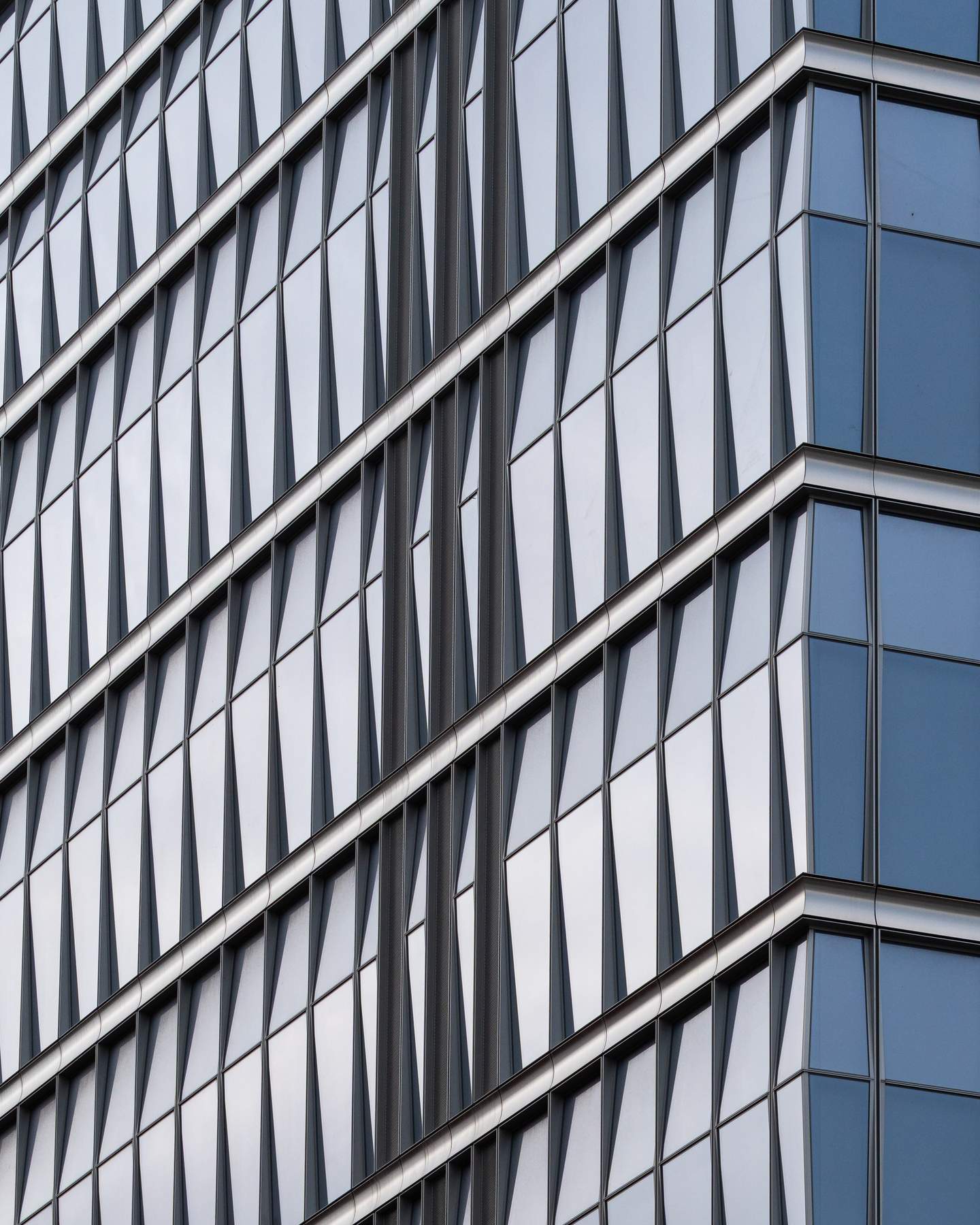 A Manhattan facade composed of undulating vertical fins - wave-form aluminum elements that create a continuous flowing pattern across the building face, surface appearing to move as viewing angle changes