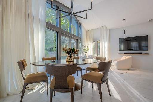 Modern dining room with floor-to-ceiling windows, sheer curtains and a sculptural pendant light