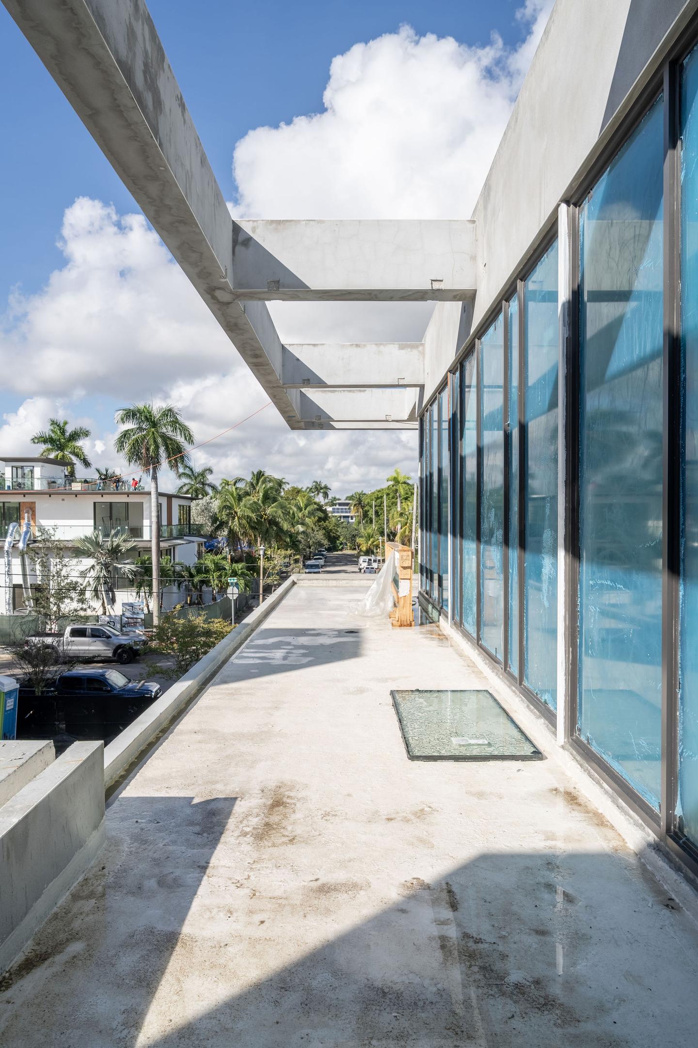 Second-floor terrace walkway with black-frame glazing looking toward the street